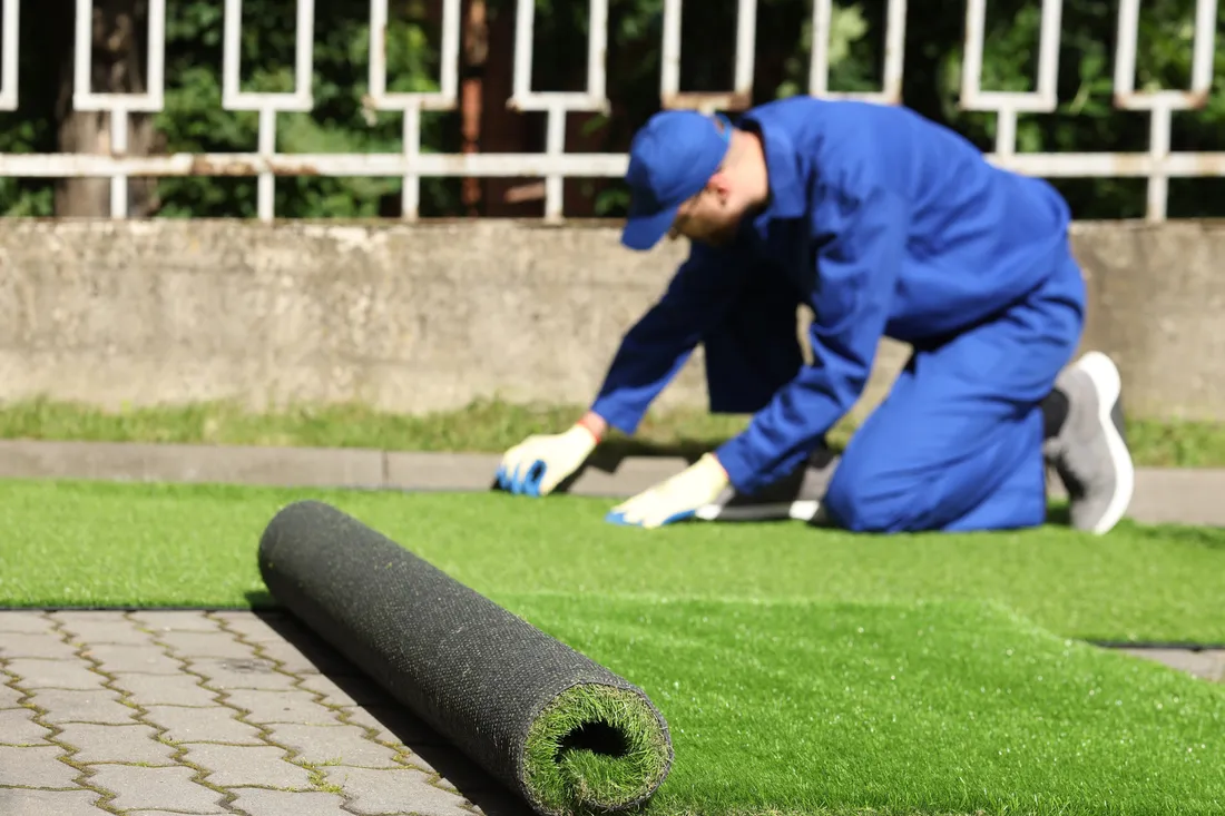 Artificial turf being rolled out across a prepared residential lawn